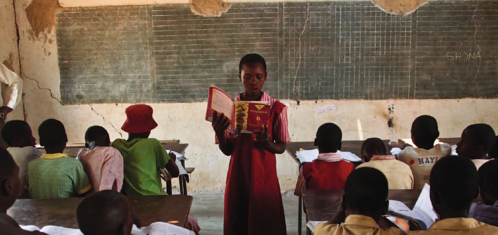 Patience, an eleven-year-old primary school student in Kachamaenza, rural Zimbabwe, reads at the front of her classroom. With help from her teacher, she can now read in her native Shona language and English // Credit: Tsvangirayi Mukwazhi / Save the Children