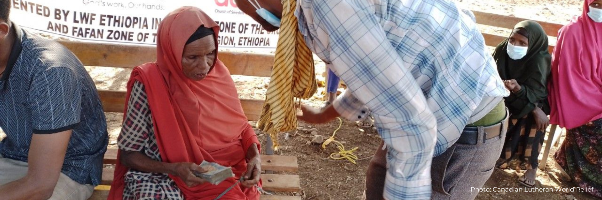 Elderly woman receives cash to help her buy food to survive the drought