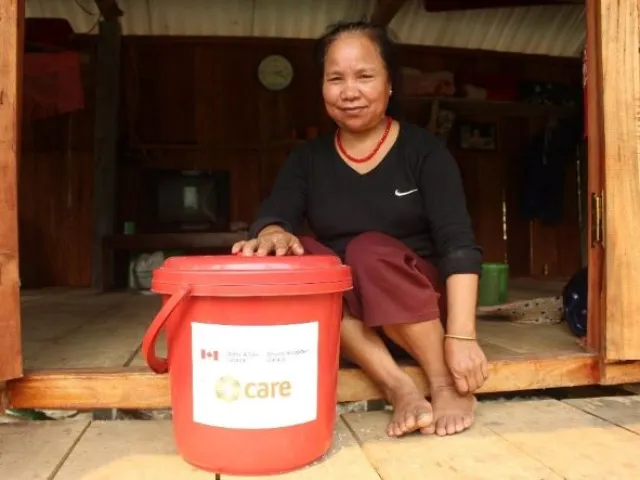 A woman kneels behind a bucket of hygiene supplies