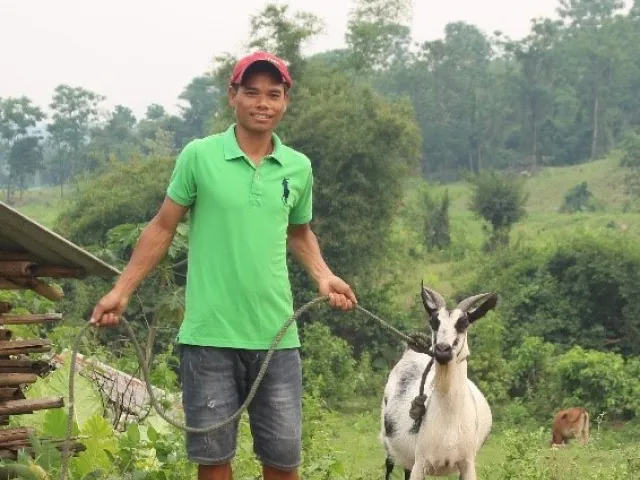 Vietnamese man stands with goat purchased with help of CARE Canada