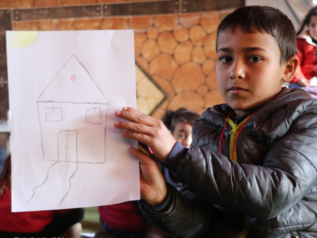 Basel, 6 years old, holding a drawing of his house