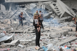 Father carrying a child in the rubbles in Gaza